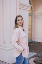 A woman wearing a pink jacket with a suede feel, featuring functional buttons and pockets.